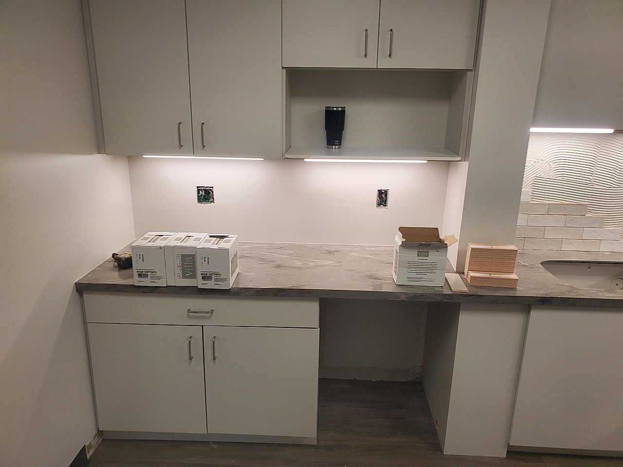 Empty butler pantry before backsplash installation, bare wall above marble countertop