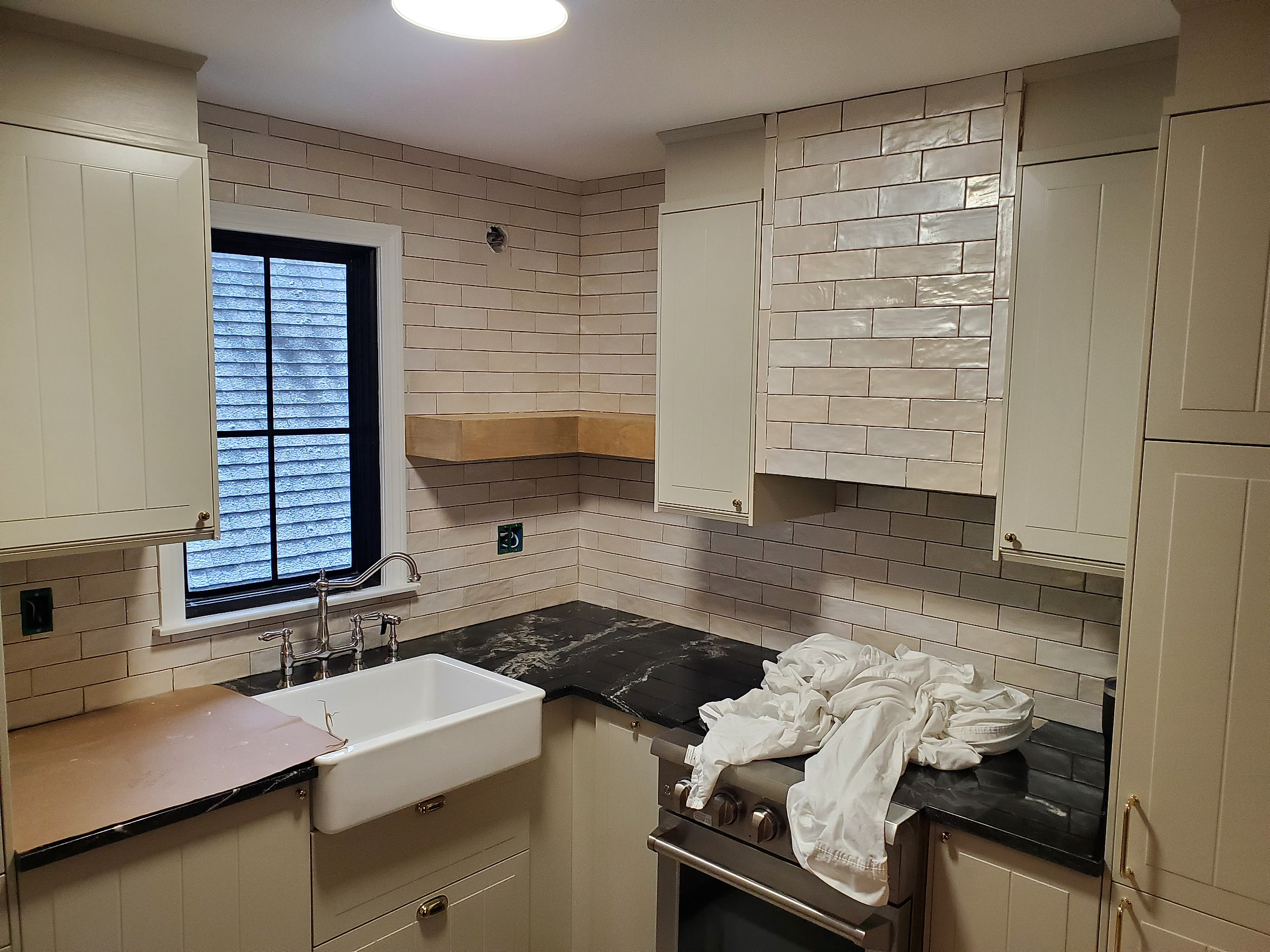 White subway tile backsplash with farmhouse sink and brass fixtures, completed kitchen